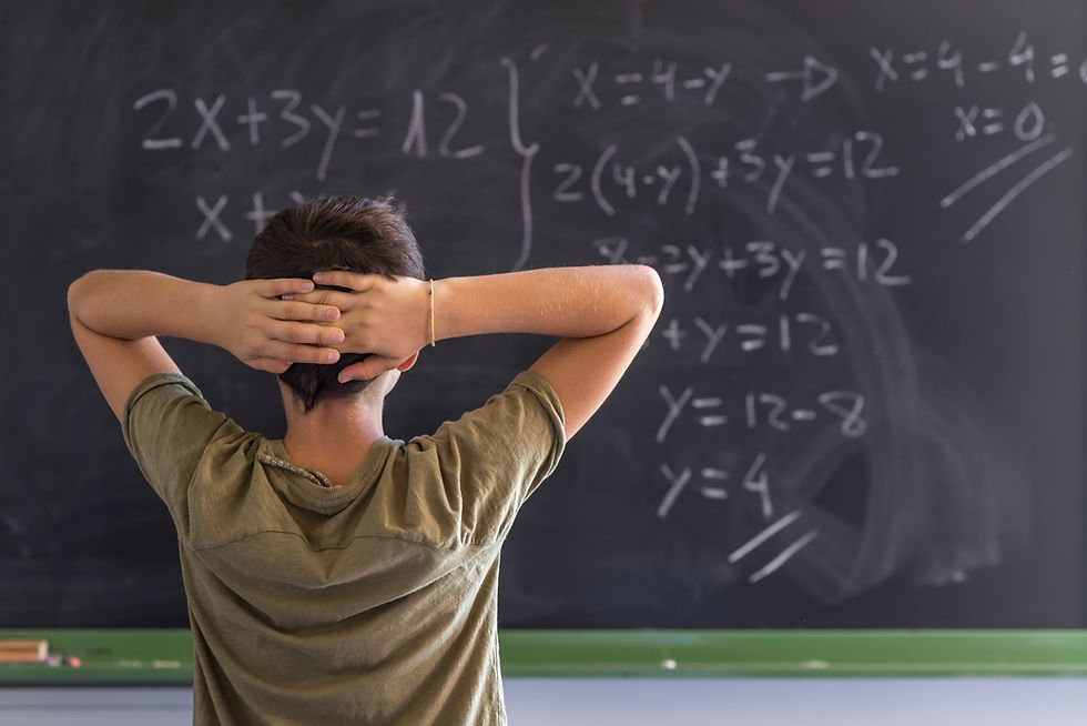 Kid experiencing Math Anxiety in standing in front of a chalkboard with a math equation written in chalk