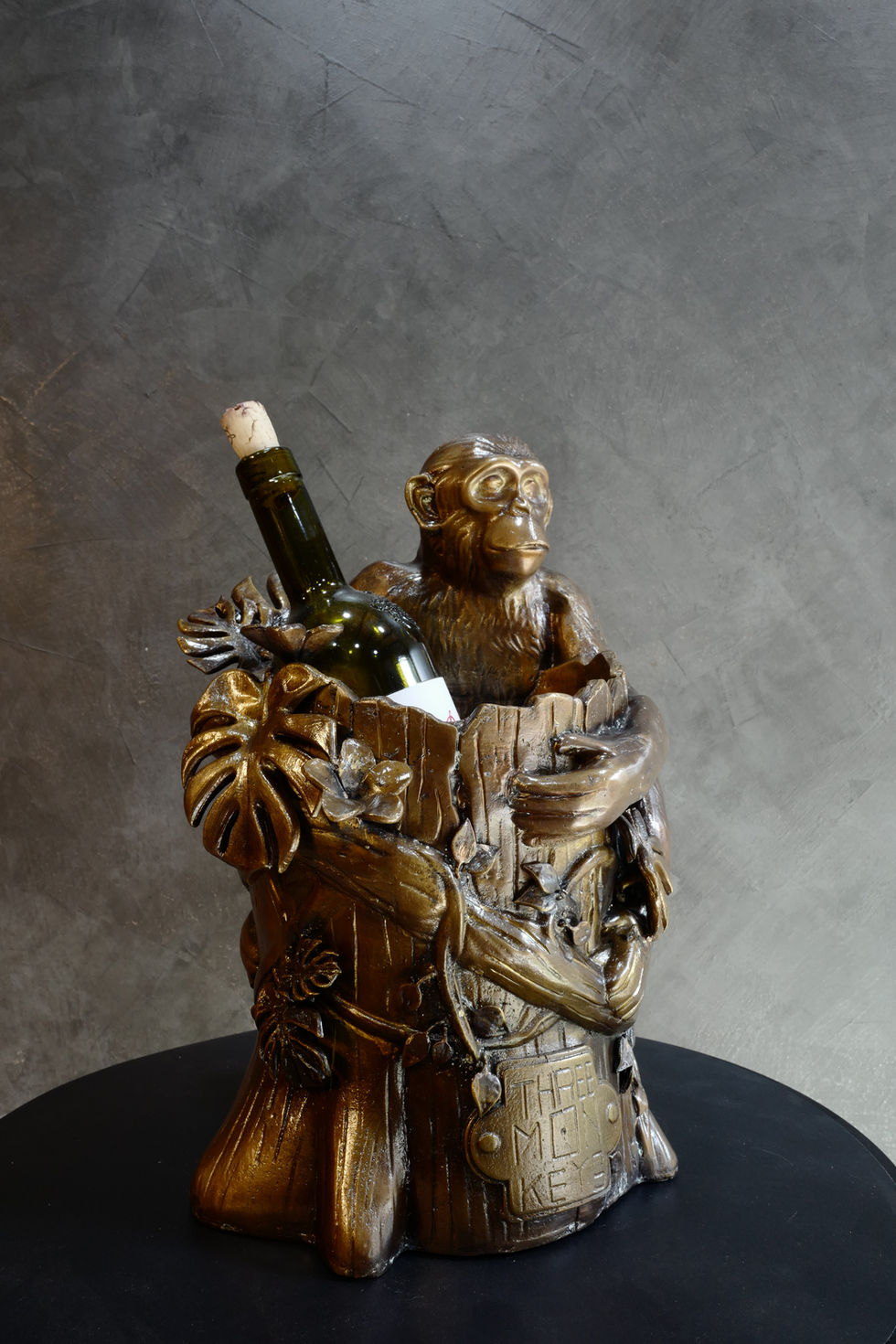 Functional brass sculpture of monkey climbing tree holding wine bottle