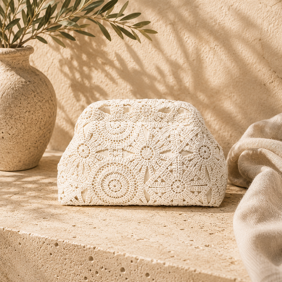 The Paloma Clutch in cream crochet with an intricate floral pattern, displayed on a travertine surface in a Mediterranean-ins