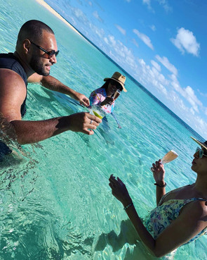 Friends sipping champagne in the Pacific Ocean. Leleuvia island resort.