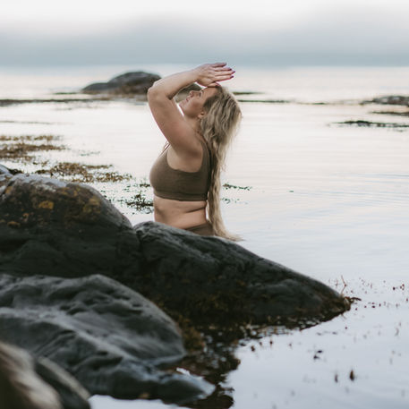 Kvinne som beveger seg i vannkanten i mykt lys