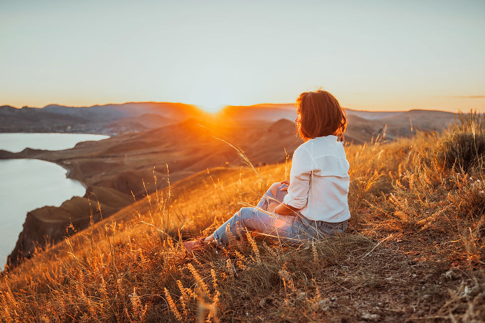 A beautiful young woman tourist is sitting on top of a mountain and enjoying the view of t