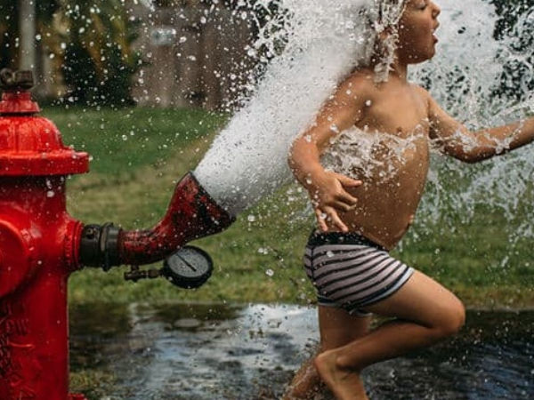 the boy playing in water coming from the tube well