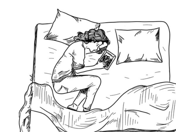 A woman laying on the bed and looking at a photo