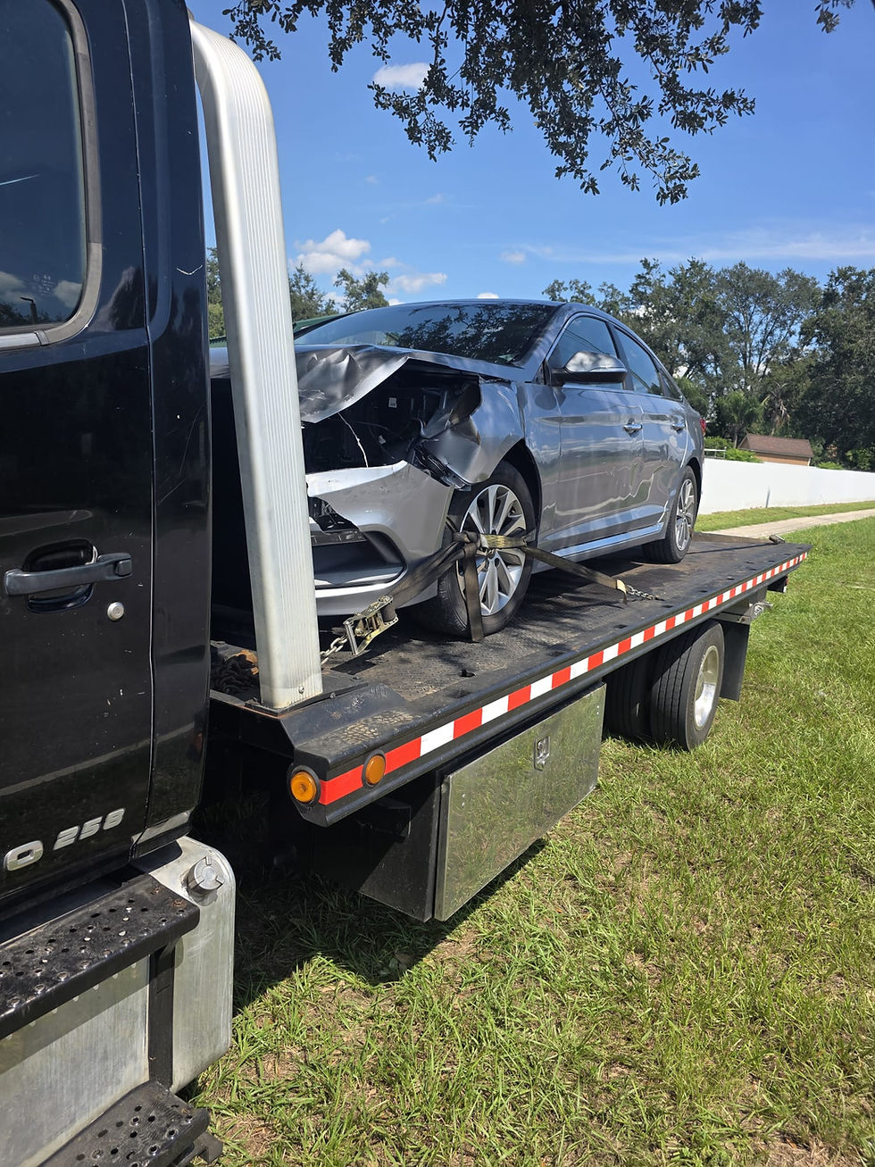 Heavily damaged dark car on flatbed tow truck for instant cash.