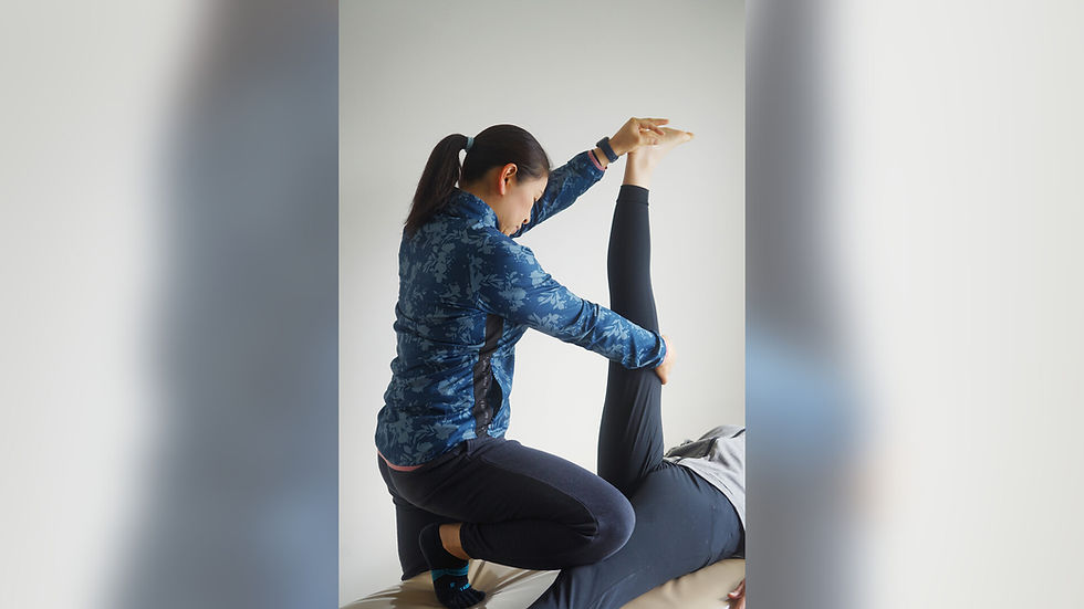 ベッドに寝たお客様の脚を伸ばすパーソナルストレッチの様子