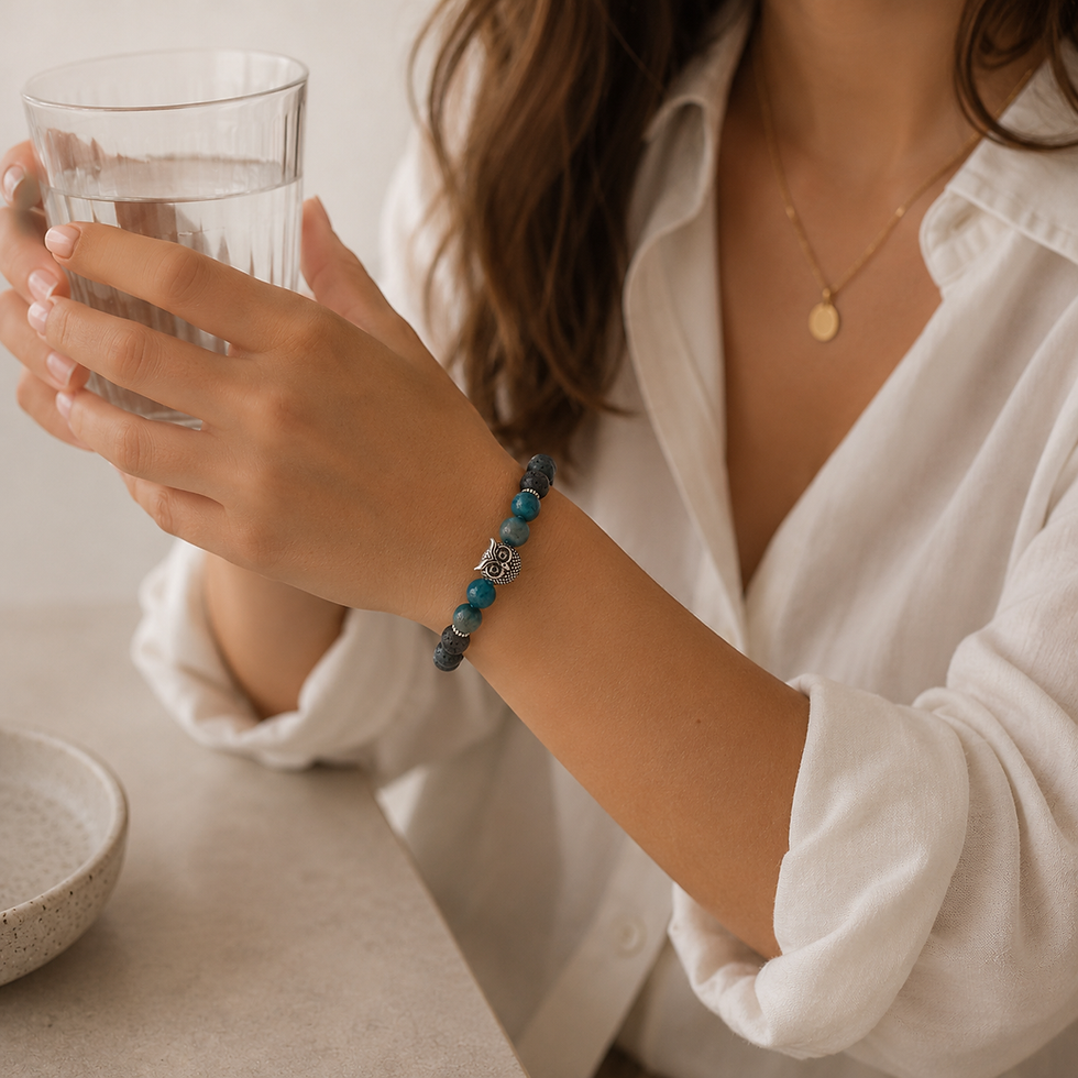 Frau trägt ein Edelsteinarmband mit blauem Tigerauge, Apatit und Labradorit am Handgelenk und hält ein Wasserglas.