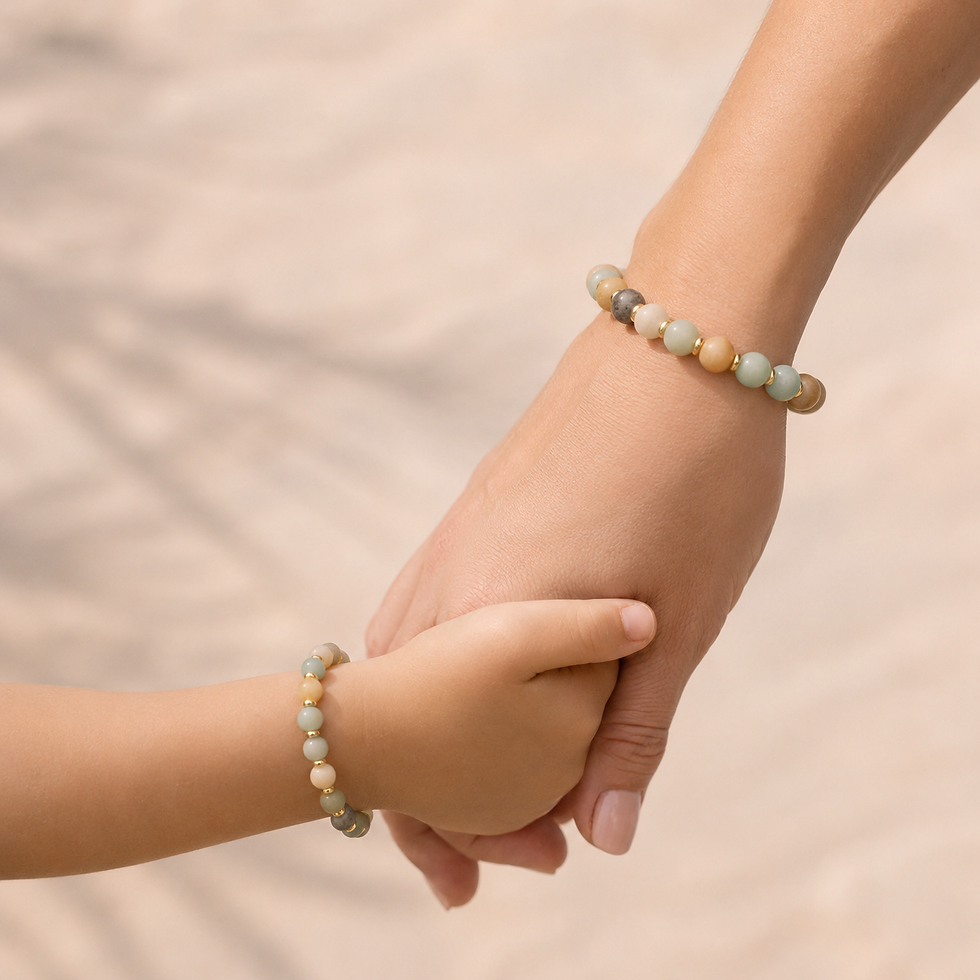 Mama und Kind halten sich an den Händen und tragen passende Aurora Light Edelsteinarmbänder mit Amazonit und goldfarbenen Akz