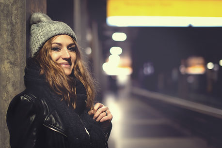 Urbanes Portrait einer jungen Frau mit Mütze am Bahnhof
