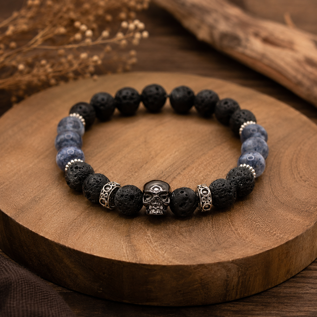 Handgefertigtes Herrenarmband aus Lavastein und Sodalith mit Totenkopf aus Edelstahl auf rustikalem Holzuntergrund