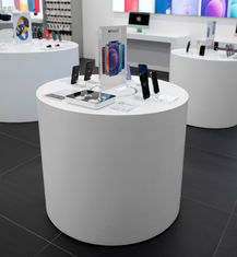 Exhibición de productos Apple con el iPhone 12. Iplace, mesas blancas exhiben teléfonos y accesorios.