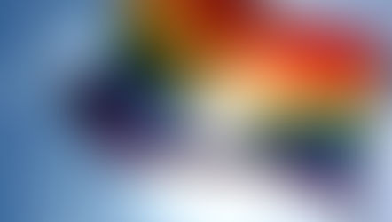 Foto de uma bandeira LGBT com céu azul de fundo