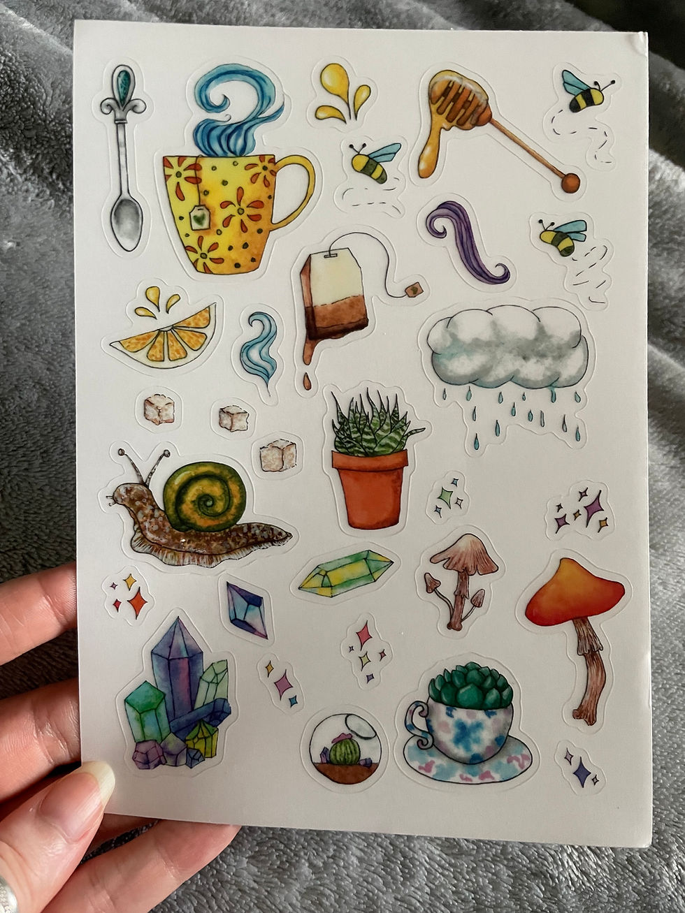 A sticker sheet of a variety of cozy items like a mug, tea, a snail, mushrooms, and crystals.