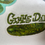 Thumbnail: A sticker of a watercolor pickle with the words "gimme dat" on a piece of paper that shows the background of the sticker is clear