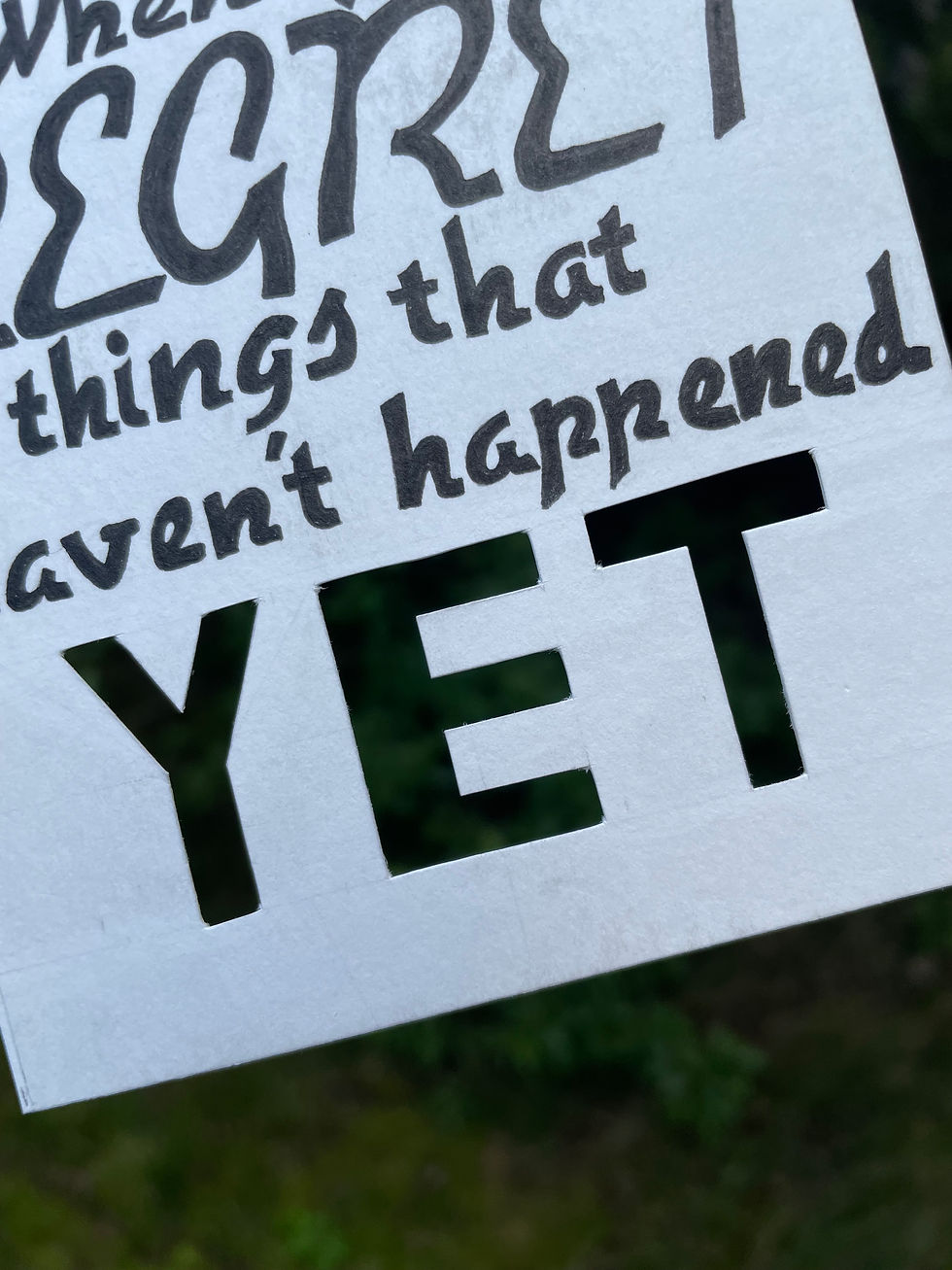 Thumbnail: A detail shot of the word "yet" that has been cut out of the paper so you can see what's behind the piece of art