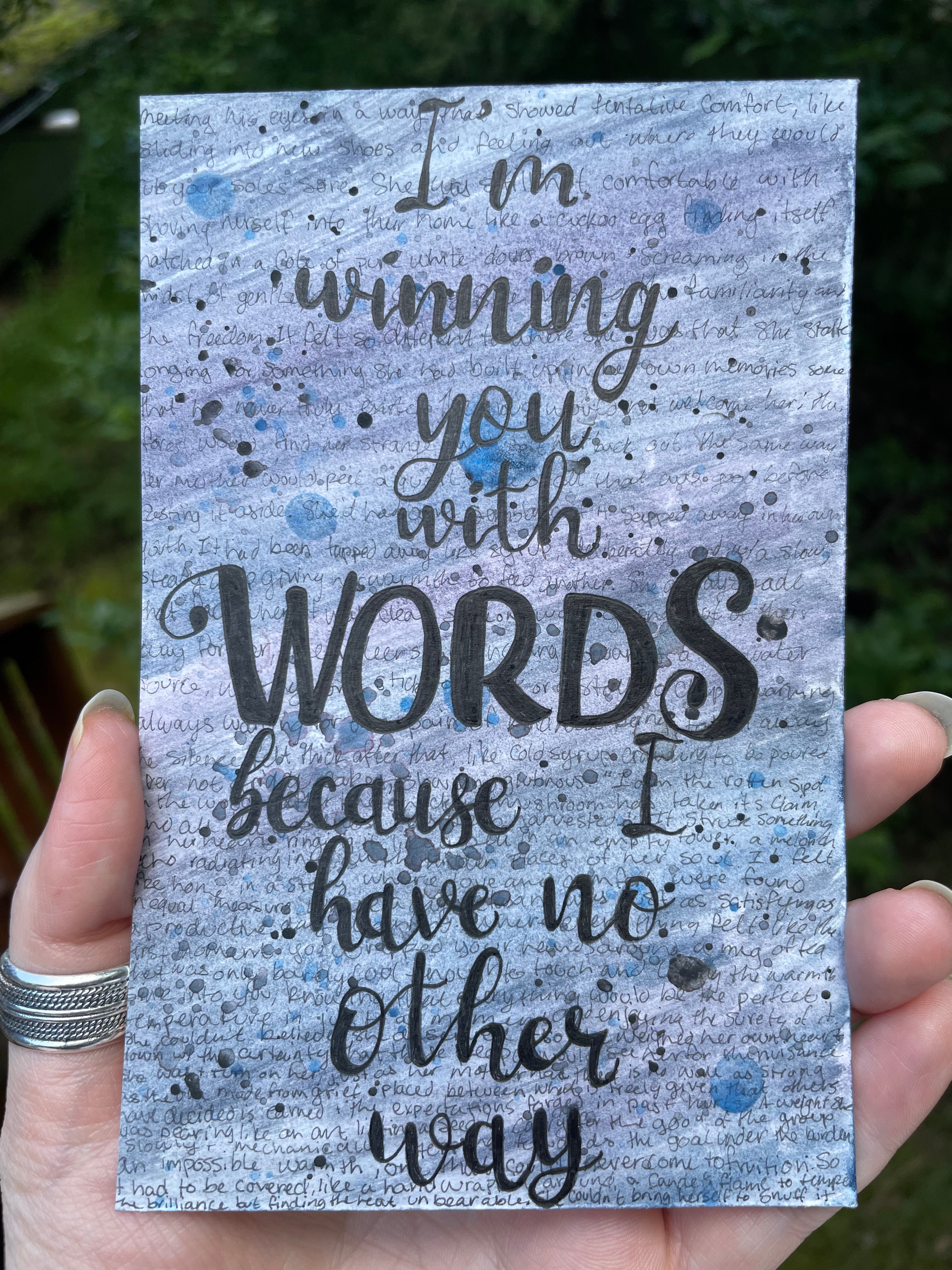 A blue, grey, and purple background with small words written all over and a forefront of the words "I'm winning you with words because I have no other way"