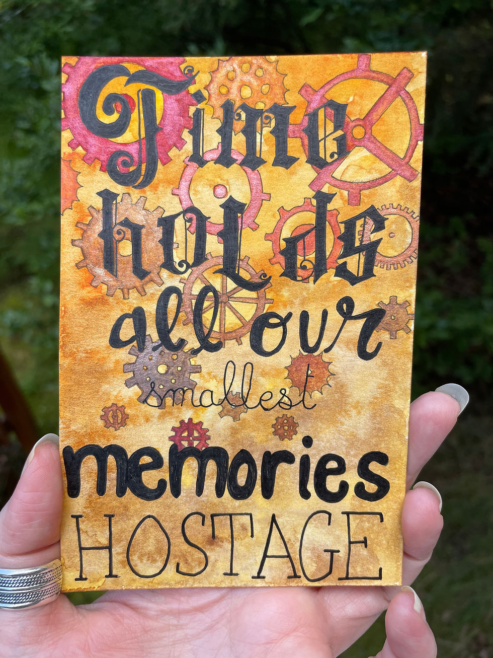 A painting of a set of cogs with the words "time holds all our smallest memories hostage"