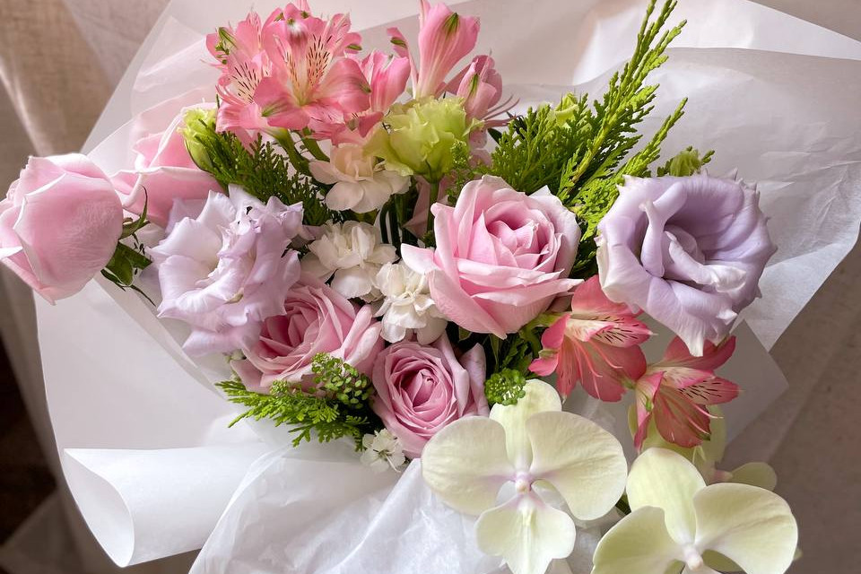 A beautiful bouquet of pink roses with lilac lisianthus and pink alstroemerias, spray carnations and phalaenopsis orchid