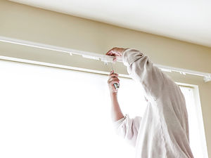 House painter reinstalls a drapery rod RM