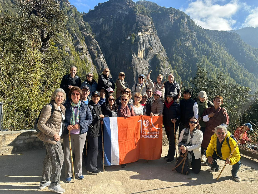 Grupo de cerca de 30 viajantes com uma montanha ao fundo, no Butão.