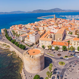 A beleza da Sardenha  é quase sempre associada à sofisticação da Costa Esmeralda  – e não à toa. A região é mesmo um dos cartões-postais  mais famosos do Mediterrâneo. Mas basta pouco tempo para a imagem se multiplicar em nuances, sotaques e paisagens . Cada canto da ilha conta sua própria história , com línguas, hábitos e sabores que resistem ao tempo , revelando a Sardenha em suas camadas . Cagliari, capital vibrante no extremo sul, ainda carrega a força de antigas muralhas  e das  influências espanholas, romanas e árabes . Não só na arquitetura – mas também nas ruelas do bairro de La Marina, nos mercados, nas torres que pontuam a cidadela. Ao redor, a região de Sulcis Iglesiente  expõe uma Sardenha mais rústica , de praias quase intocadas e tradições que seguem vivas , como a produção artesanal do bisso, a “seda do mar” . Do outro lado, Alghero tem alma catalã e jeito medieval , com muralhas voltadas para o mar. Ali perto, Bosa surpreende com seu casario colorido e atmosfera boêmia . Já Porto Cervo e a Costa Esmeralda , no norte, reforçam a imagem de exclusividade: vilas de luxo, mar turquesa  e uma marina que atrai iates do mundo todo. Mas mesmo ali, entre  grutas esculpidas e aldeias no interior , é possível sentir o peso da tradição – como em Calangianus , onde o trabalho com a cortiça  e os rituais à mesa seguem quase intocados . Viajar por essas regiões, dentro de um mesmo itinerário, é como atravessar países diferentes , unidos apenas pela geografia e pela força das raízes sardas. Sabores de uma ilha plural A cozinha sarda é uma síntese fiel da geografia da ilha : do interior montanhoso ao mar translúcido, tudo encontra espaço à mesa . Na costa, brilham os f rutos do mar – ouriços, polvos, bottarga . No interior, são os queijos intensos, o porceddu  (leitão assado lentamente) e os pães elaborados  como o carasau que contam a história de um povo ligado à terra . Durante o roteiro, algumas dessas tradições ganham forma em experiências locais . É o caso da vinícola visitada na região de Sulcis Iglesiente , onde além da paisagem, o destaque é o Carignano, tinto encorpado típico do sul da ilha. Em Calangianus, a degustação do licor de mirto  – produzido a partir das bagas da planta nativa – ajuda a entender a importância dos sabores na cultura sarda . Mais do que provar, é um convite a perceber como os sabores da Sardenha são parte viva da identidade local . Conheça esse e outros destinos com a Domundo! Transformamos viagens  em experiências  que conectam pessoas, lugares e culturas,  com um jeito único de fazer turismo: artesanal, cuidadoso e comprometido em estar sempre no lugar certo, na hora certa. Quer programar a sua próxima viagem? Fique por dentro dos nossos roteiros.