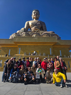 Grupo de cerca de 30 viajantes posando em frente à estátua do Buda sentado, no Butão.