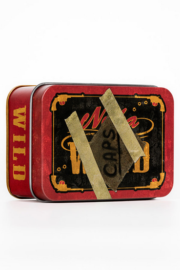 Nuka-Cola Wild from Fallout themed metal tin that comes with 20 matching bottle caps. The front of the tin has a Nuka-Cola Wild label that has the look of a handwritten note that says 'CAPS' taped on front, all gold, black and red colorway. The loose bottle caps have the Nuka-Cola Wild logo in a cowboy script font on the front of the cap, with the inside of the bottle cap a silver color