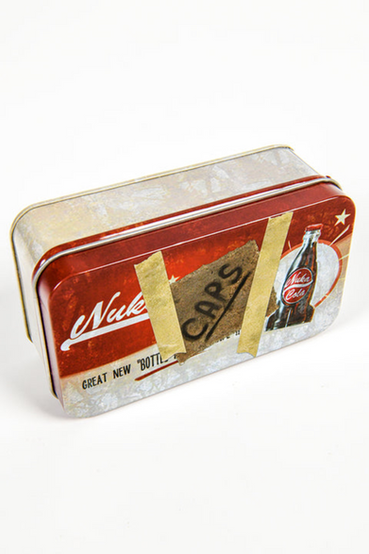 Classic Nuka-Cola from Fallout themed metal tin that comes with 20 matching bottle caps. The front of the tin has a Nuka-Cola advertisement that has the look of a handwritten note that says 'CAPS' taped on front. The loose bottle caps have the Nuka-Cola logo in white printed on red, with the inside of the bottle cap a gold color
