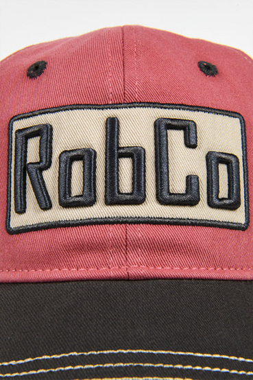 Trucker hat featuring a 3D embroidered RobCo logo from Fallout on the front, with light red/beige panels, and a curved black bill with beige contrast stitching