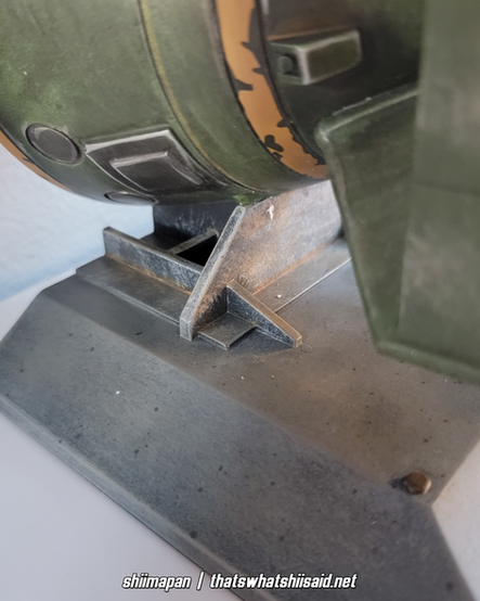 A set of bookends modeled after a mini nuke from Fallout 4, also pictured with a large silver enamel pin of Liberty Prime tossing a mini nuke