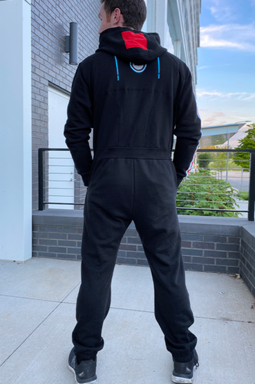An N7 from Mass Effect themed onesie or kigurumi, which is all black and has the signature N7 red/white stripe on the right arm, N7 embroidery over the right chest, and custom N7 printed fabric on the hoodie