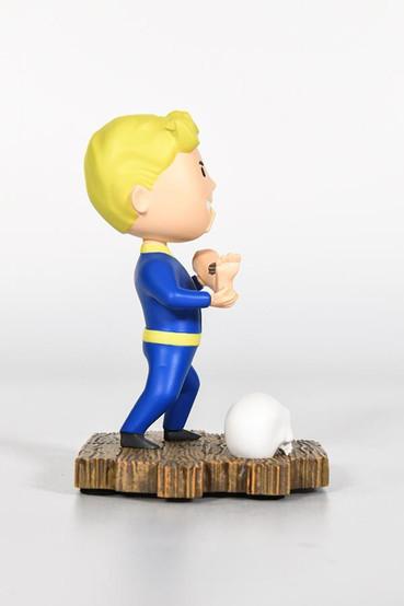 Mini statue based on the Cannibal perk from Fallout, technicolor variant. Vault Boy is grinning while eating a dismembered leg, a skull and hand is by his feet