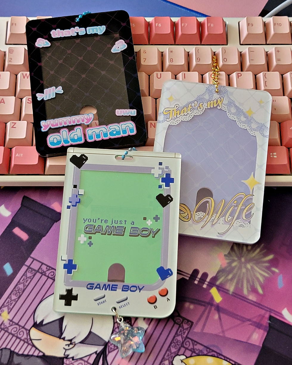 photocard holders: that's my yummy old man in light pink and light blue on a black background, That's my Wife in yellow on a white and lavender background, and you're just a GAME BOY styled after the Nintendo Gameboy