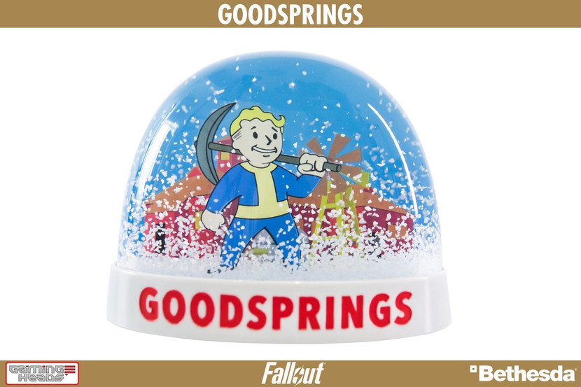A real life collectible plastic snow globe based on Goodsprings as seen in Fallout: New Vegas. Vault Boy is shown with a pick axe slung over his left shoulder, with a house and windmill in the background. The snow globe has a clear plastic dome, with a white base that says GOODSPRINGS in capitalized red text on the front