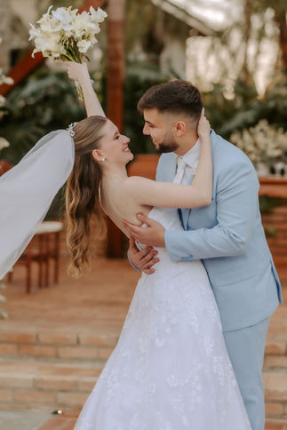 Noiva sorrindo e olhando para baixo segurando buquê de flores brancas em quarto elegante
