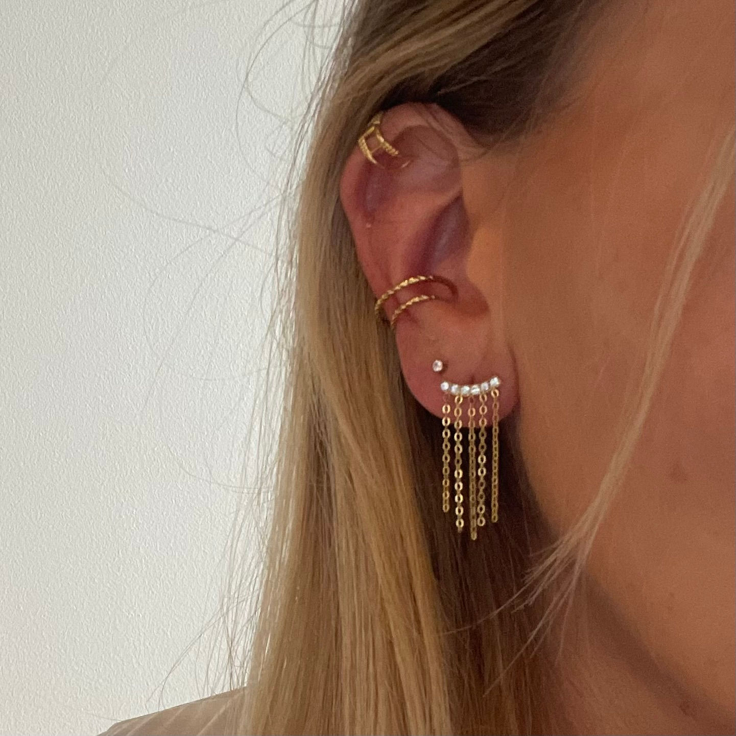 Ces boucles se composent d’une petite barre dorée d’où tombent de fines chaînes façon franges. Elles créent un joli mouvement