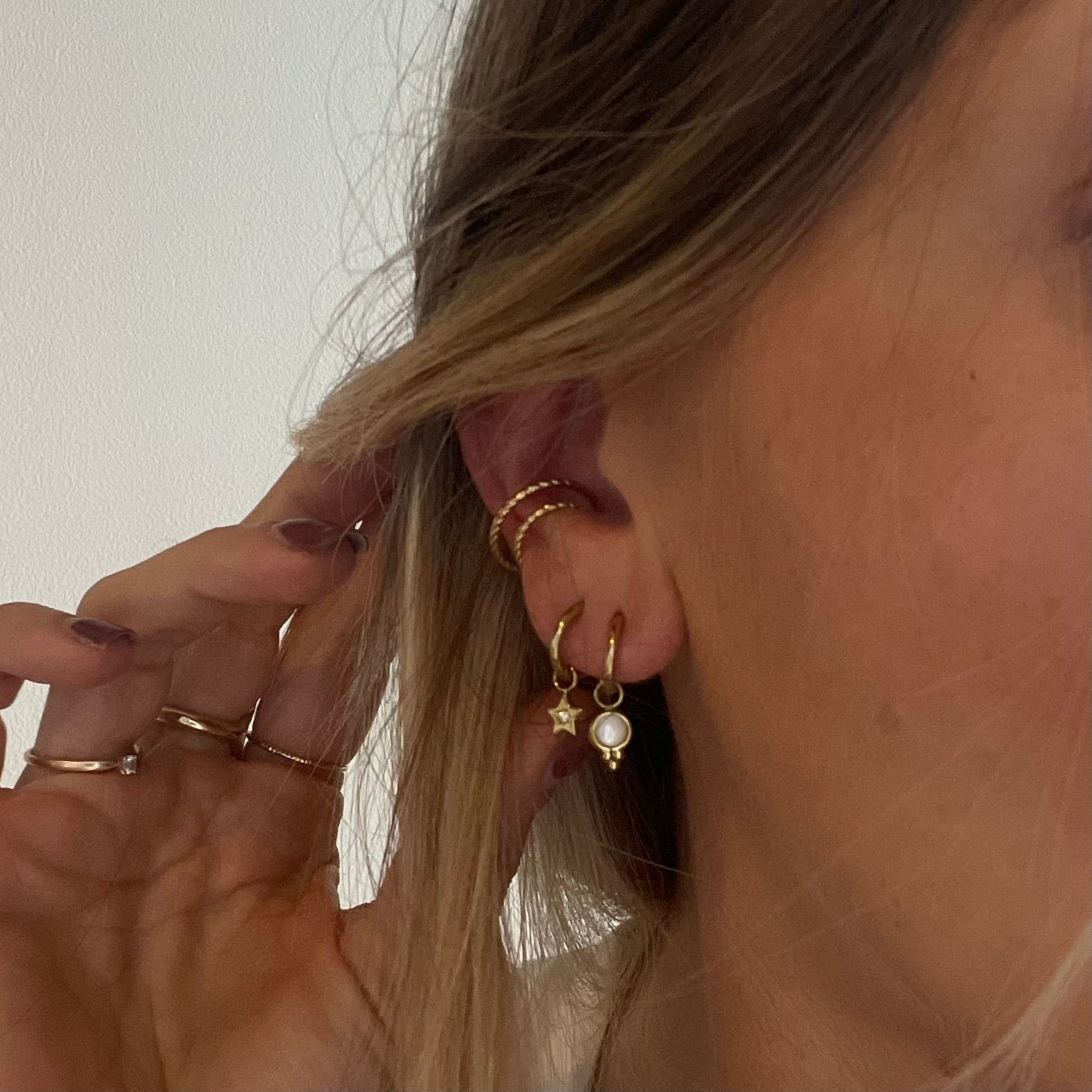 Créoles lisses avec petit charm perle ivoire et micro-boules dorées. Un classique doux et féminin qui fonctionne avec tout.