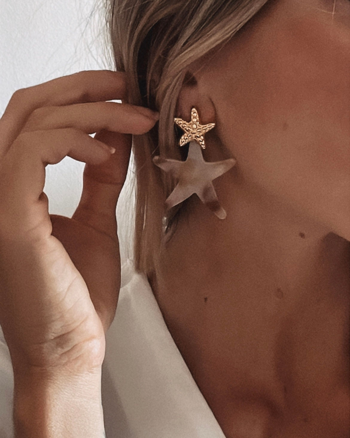 boucles d'oreilles acrylique de forme étoile, sur un ton beige fumé, décorée aussi d'une étoile de mer dorée