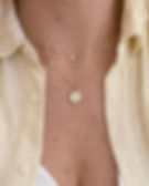 collier délicat au mouvement léger, ponctué de petites pampilles dorées et d’un détail pierre claire qui capte joliment la lu