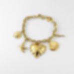 Un bracelet doré au charme solaire, orné de cinq breloques symboliques : cœur, oiseau, coquillage, soleil et corne porte-bonh