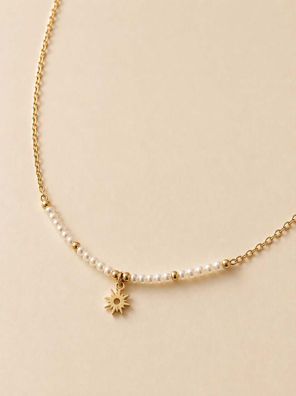 Un collier solaire, composé d’une chaîne dorée, d’un rang de petites perles et d’un mini pendentif soleil. Disponible en vari