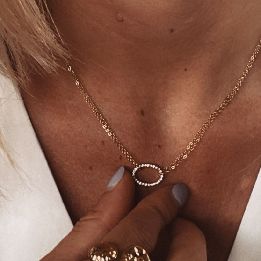 Collier fin élégant, la chaîne est doublée et est décorée d'un médaillon ovale serti de zirconiums.