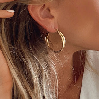 femme portant une boucle d'oreille dorée tube epaisse