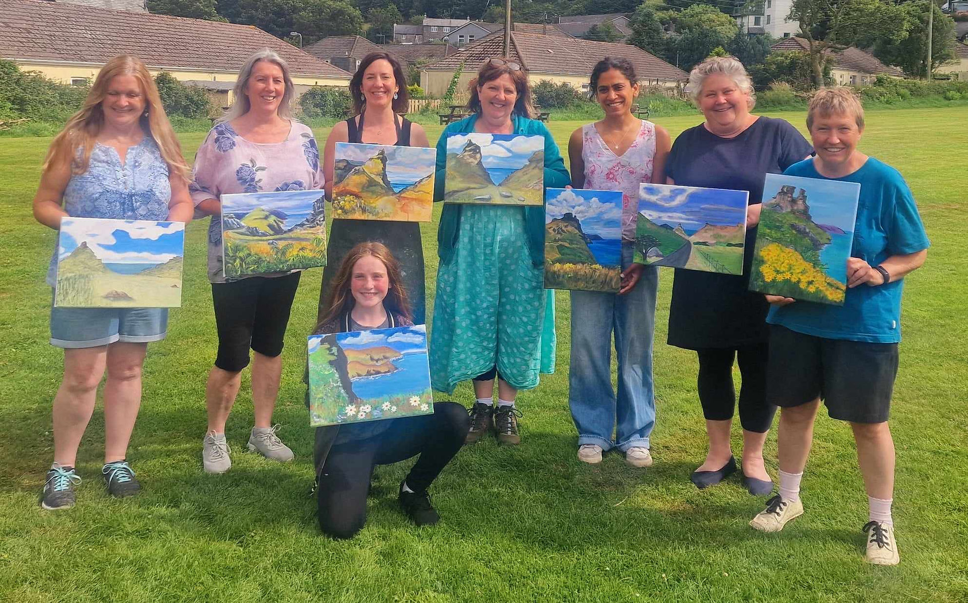 Artists all stood together holding their individual paintings of The Valley of Rocks created with artist Amy Jobes on retreat with Lone Pine in Exmoor