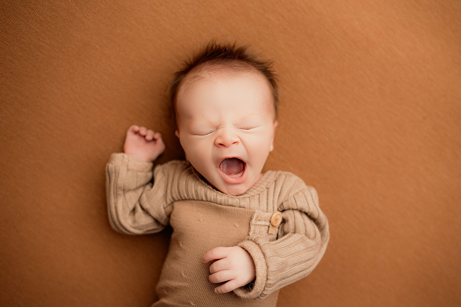 Baby boy in a long-sleeved outfit, stretching his arms and yawning