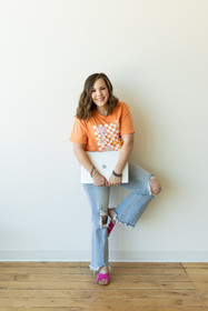 Rachel leaning against a wall with her computer in hand, smiling at camera