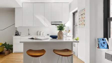 Modern white kitchen with island and wood bar stools.