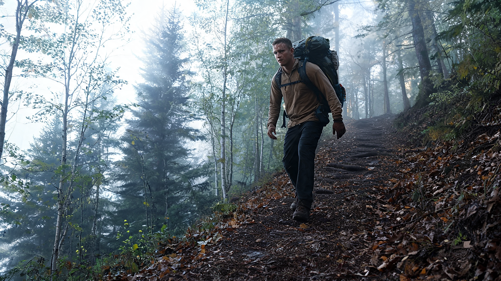 A person rucking with a heavy pack up a forest trail in morning fog