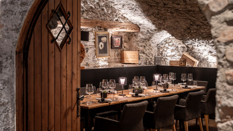 Blick durch eine historische Holztür auf eine elegant eingedeckte Tafel für exklusives Private Dining im Natursteingewölbe des Weererwirts
