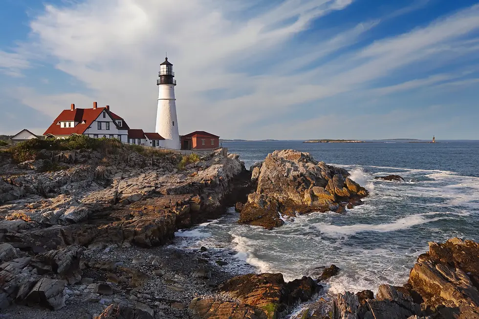 White lighthouse on rocky shore with red-roofed house